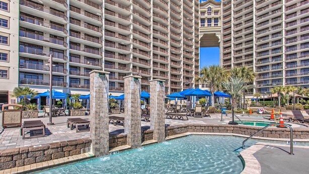 A hotel pool area with a large pool, lounge chairs, and umbrellas. - Resort Perks & Pools: Townhome By Barefoot Landing (Myrtle Beach)