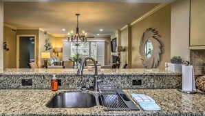 A kitchen with granite countertops, a double sink, and a modern chandelier. - Myrtle Beach Vacation Rental w/ 2 Resort Pools! (Myrtle Beach)