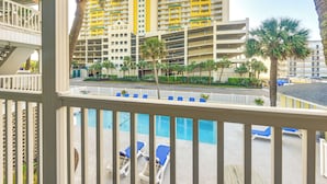 A hotel with multiple floors, outdoor pool area with lounge chairs, and palm trees. - Walkable Studio in North Myrtle Beach! (North Myrtle Beach)