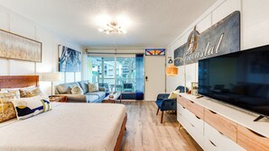 Et moderne hotelværelse med en stor seng, et fladskærms-tv, en sofa og et spiseområde med udsigt.