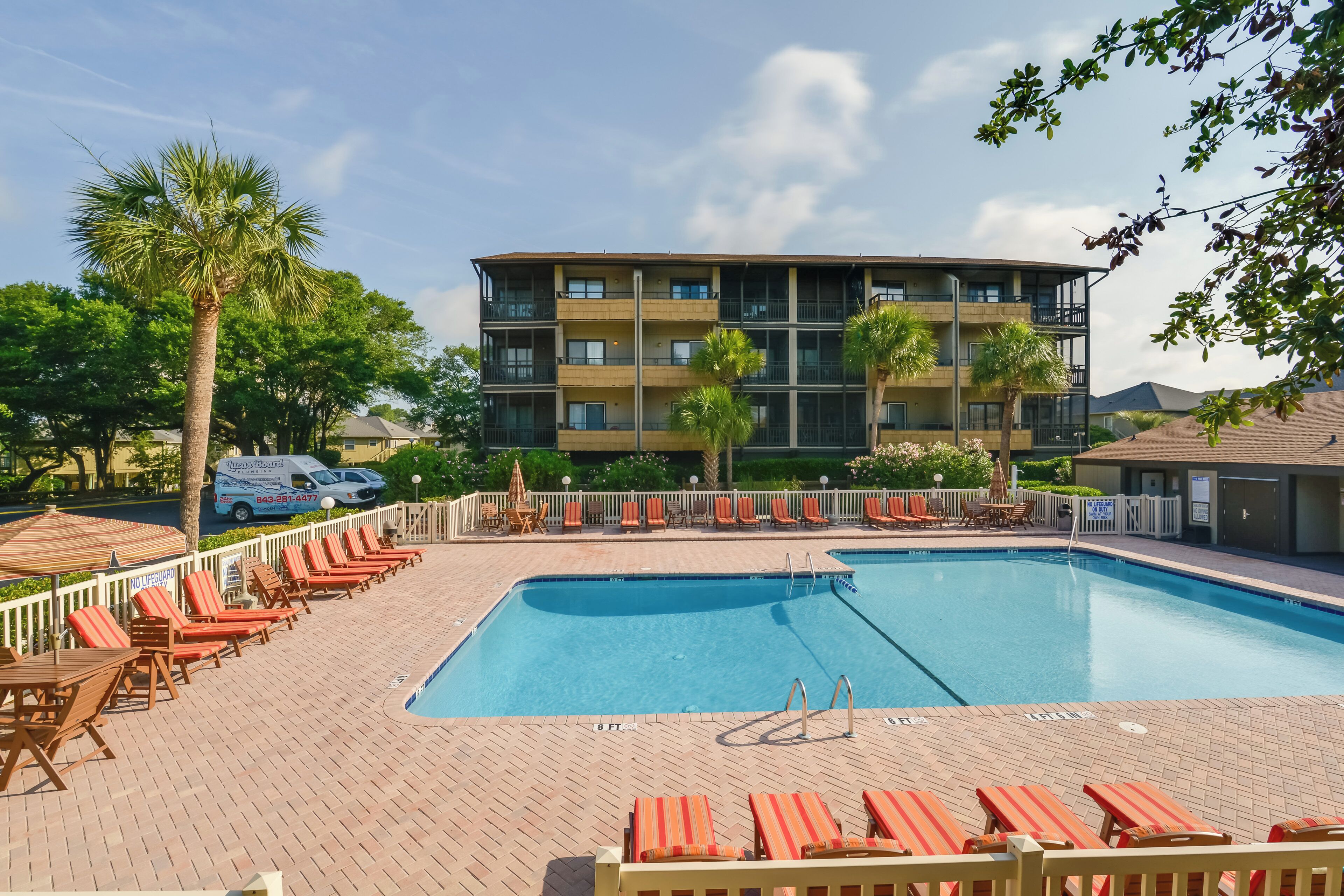 A swimming pool with lounge chairs and a building in the background.