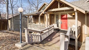 A wooden cabin with a red door, a porch, and a small deck. - Osage Beach Getaway - 1 Mi to Margaritaville Fun! (Osage Beach)