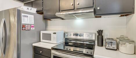 A compact kitchen with a stainless steel refrigerator, microwave, oven, and toaster.
