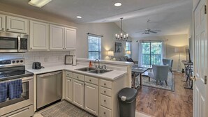 A modern kitchen with white cabinetry, stainless steel appliances, and a central island with a sink. - Pawleys Island Condo at True Blue Golf Resort (Pawleys Island)