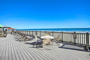 A wooden deck with chairs and a table overlooking a beach. - Oceanfront Vacation Rental in Murrells Inlet! (Murrells Inlet)