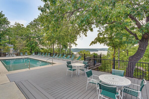 A pool area with a deck, lounge chairs, and a table with chairs.