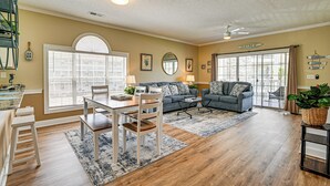A spacious living room with a dining area, large windows, and a ceiling fan. - 2 Mi to Beach: Pool-view Myrtle Beach Escape! (Myrtle Beach)