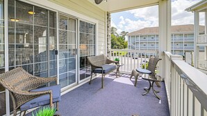A covered balcony with wicker furniture, a ceiling fan, and a view of other buildings. - 2 Mi to Beach: Pool-view Myrtle Beach Escape! (Myrtle Beach)