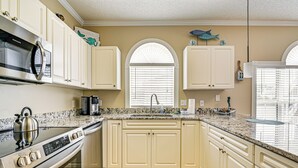 A kitchen with white cabinets, a stainless steel stove, and a granite countertop. - 2 Mi to Beach: Pool-view Myrtle Beach Escape! (Myrtle Beach)