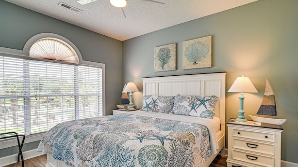 A bedroom with a bed, two nightstands, a window with blinds, and a ceiling fan. - 2 Mi to Beach: Pool-view Myrtle Beach Escape! (Myrtle Beach)
