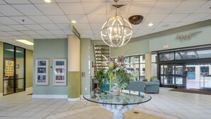A lobby with a glass-top table, a chandelier, and a staircase in the background. - Oceanfront Condo w/ Views in North Myrtle Beach! (North Myrtle Beach)
