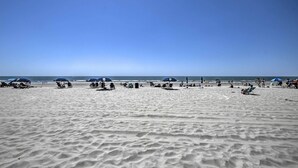 A wide sandy beach with several umbrellas and beach chairs. - Oceanfront Condo w/ Views in North Myrtle Beach! (North Myrtle Beach)