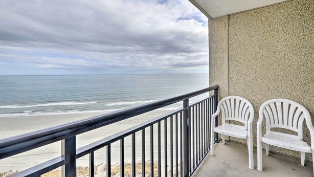 A balcony with a view of the ocean, two white chairs, and a concrete wall. - Oceanfront Condo w/ Views in North Myrtle Beach! (North Myrtle Beach)