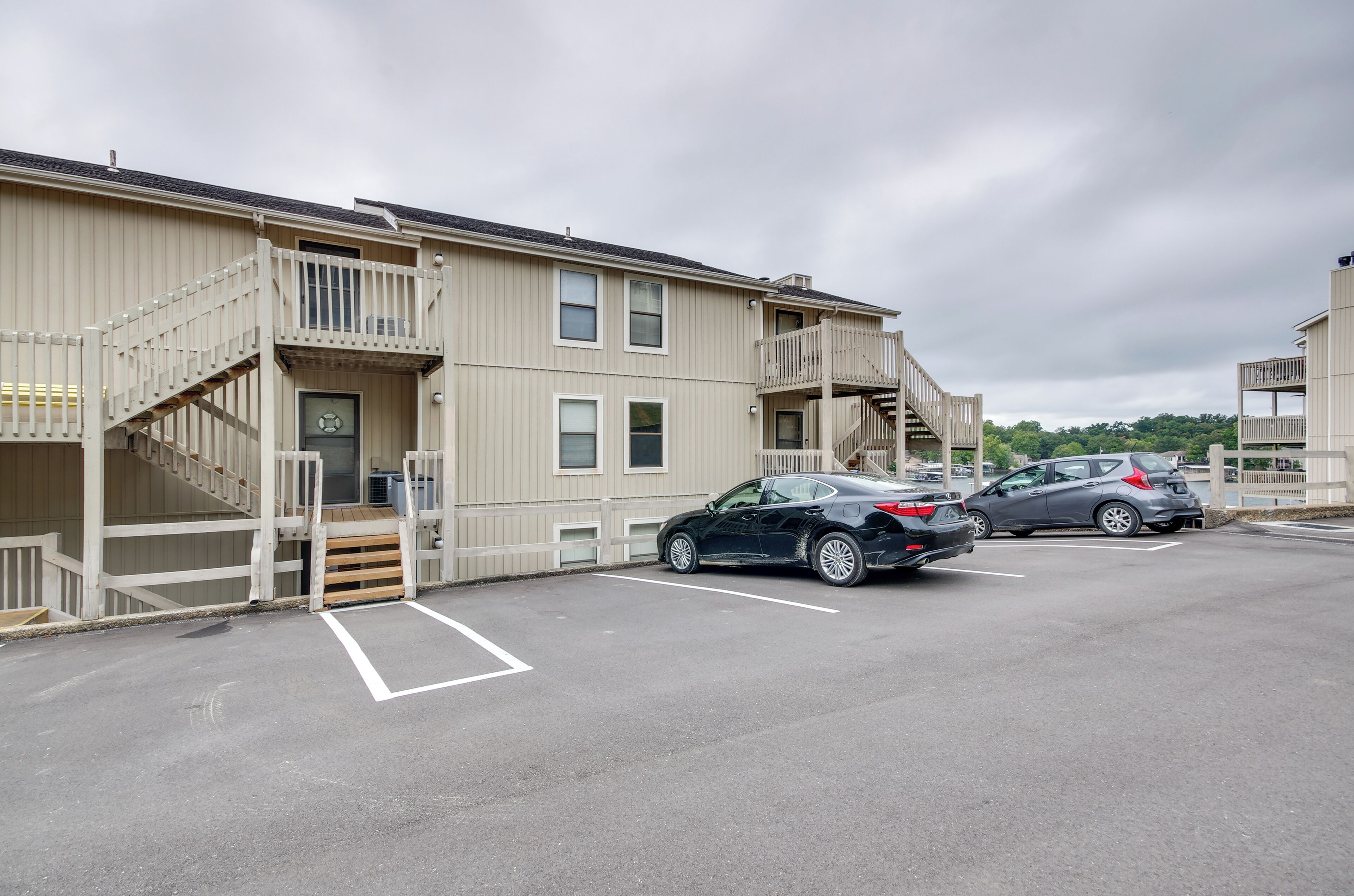 A multi-story building with a parking lot. There are two cars parked in the lot.