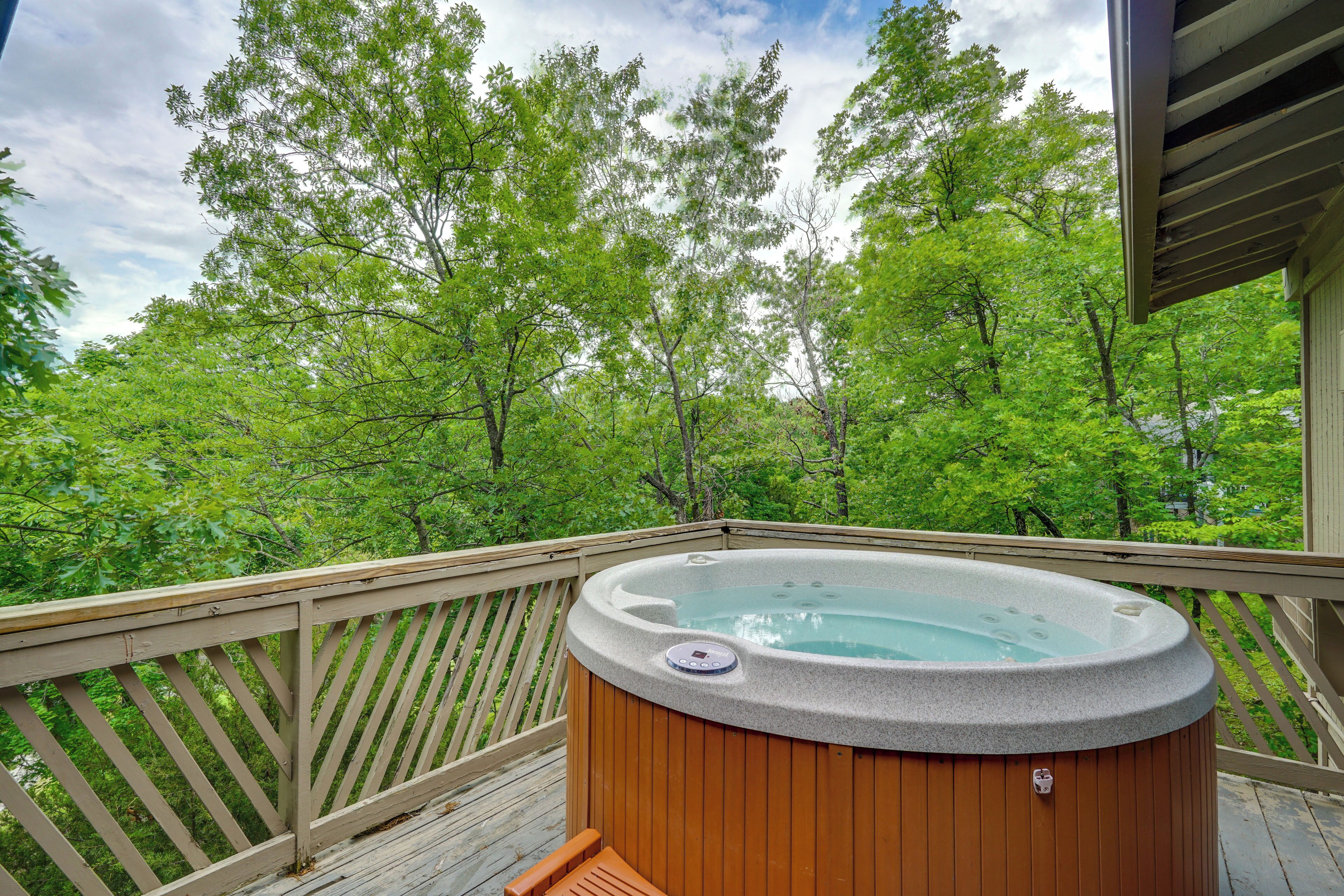 Un jacuzzi en una terraza de madera con vista a árboles verdes.