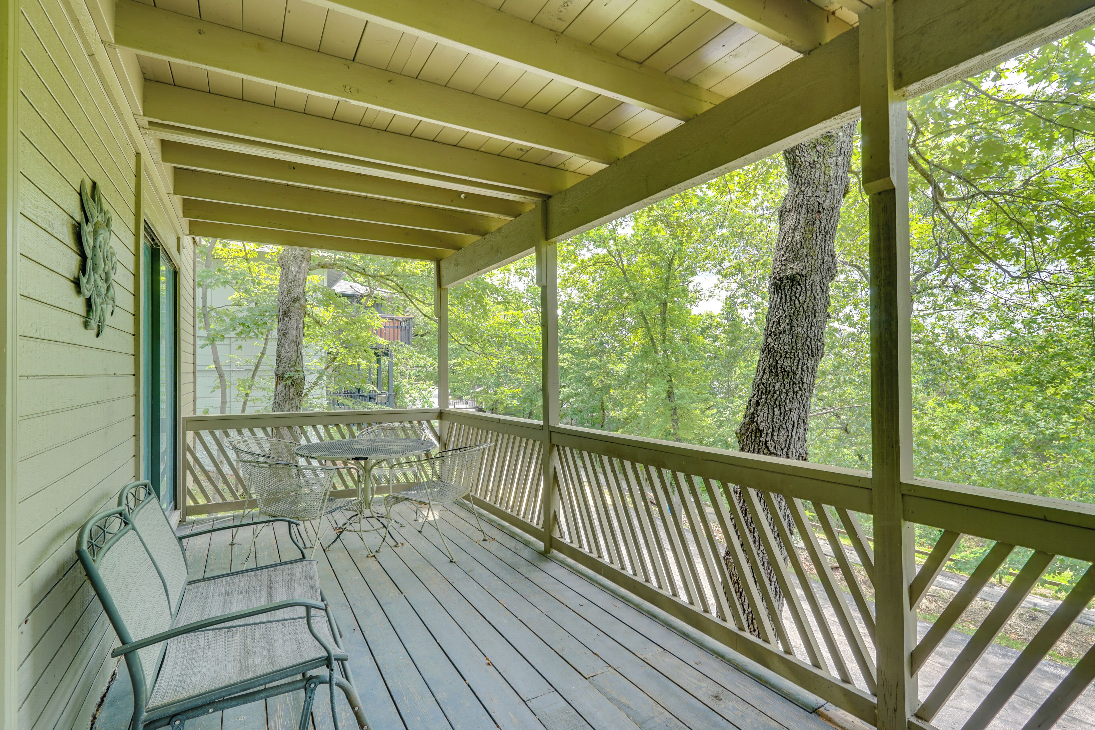 A covered porch with wooden railings, metal chairs, and a table.