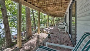 A covered outdoor area with wooden beams, brick flooring, and white striped benches. - Dock, Slide + Fire Pit: Osage Beach Lake House (Osage Beach)