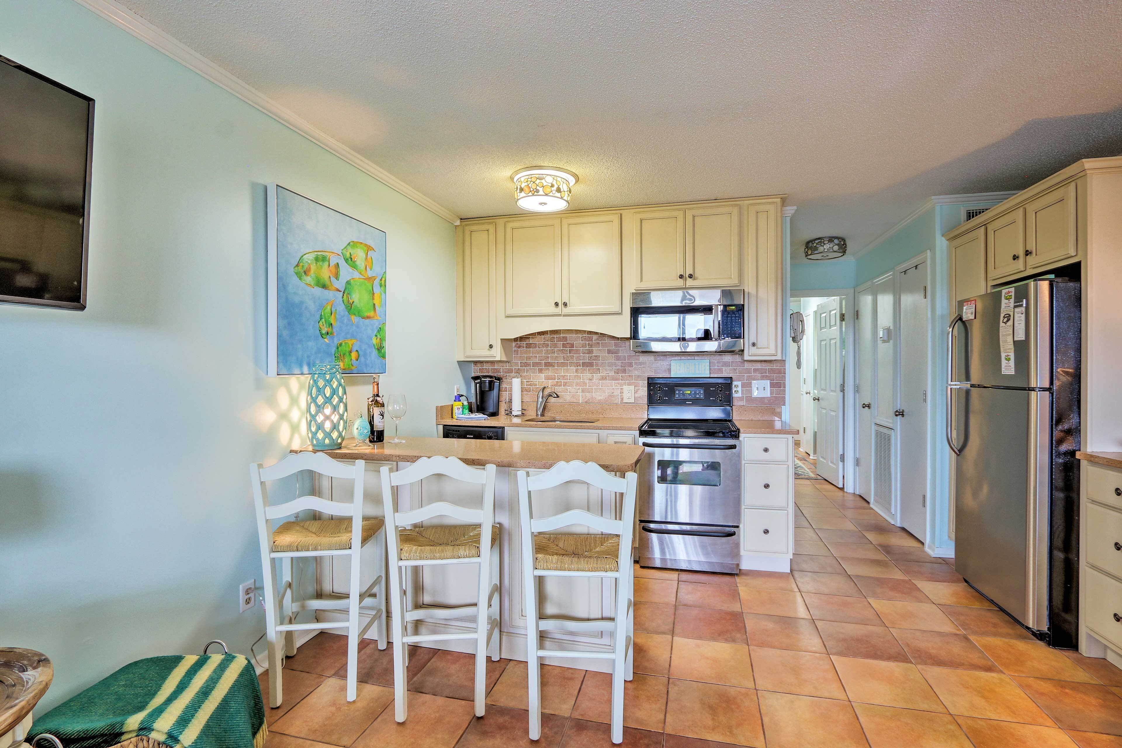 A kitchen with white cabinets, a brick backsplash, stainless steel appliances, and a wooden island with chairs.