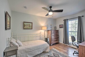 A bedroom with a bed, dresser, chair, and a window with curtains.