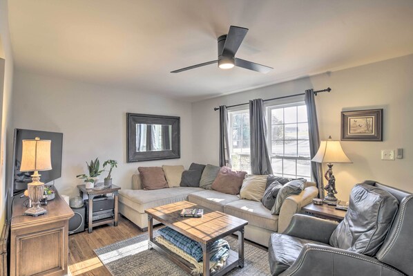 A living room with a sofa, a coffee table, a TV, and a ceiling fan.