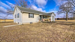 A single-story house with a front porch, a chimney, and a visible garage door. - Peaceful Missouri Home, 25 Mi to Truman Lake! (Cole Camp)