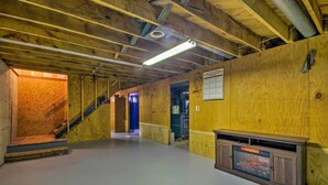 A wooden interior with a staircase, a fireplace, and a hallway leading to another room. - Peaceful Missouri Home, 25 Mi to Truman Lake! (Cole Camp)