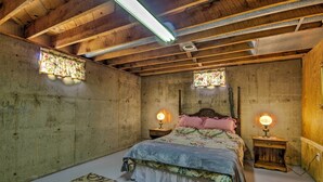 A bedroom with a wooden ceiling, a floral bedspread, two bedside lamps, and a patterned rug. - Peaceful Missouri Home, 25 Mi to Truman Lake! (Cole Camp)