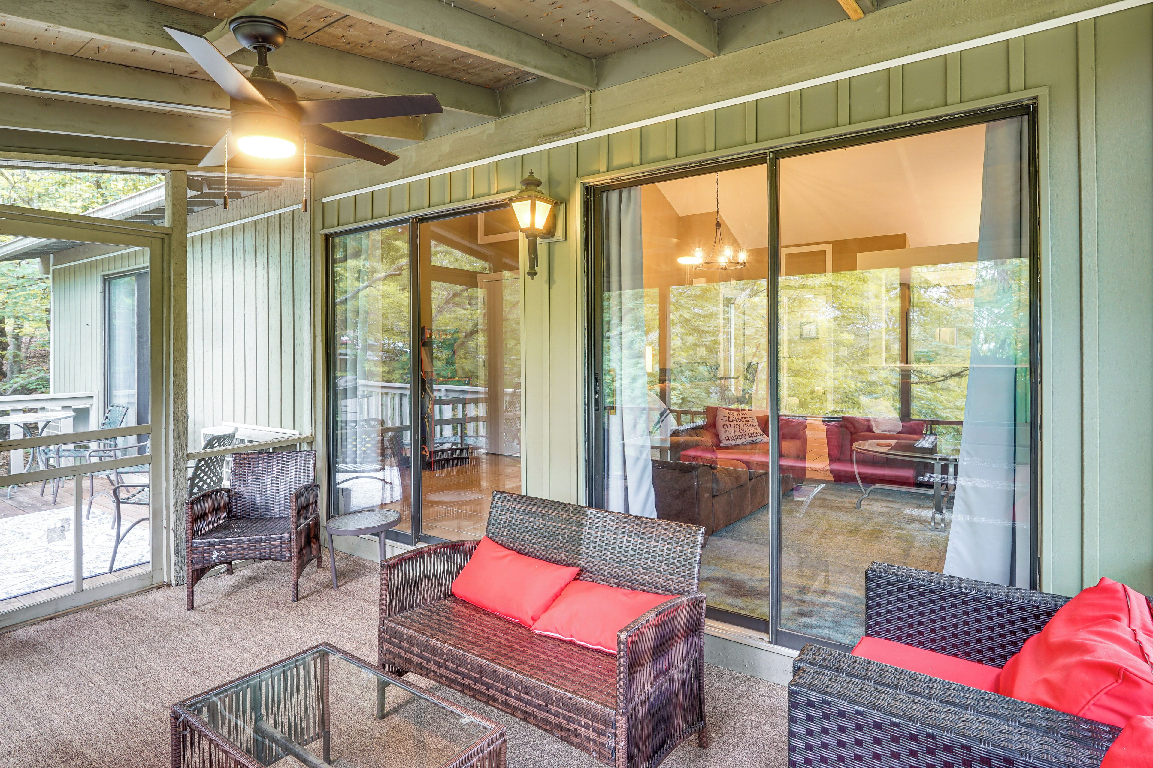 A covered outdoor seating area with wicker furniture and a ceiling fan.