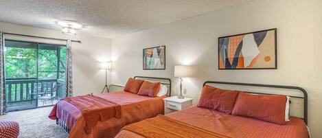 A room with two beds, a window with curtains, a chair, and a table.
