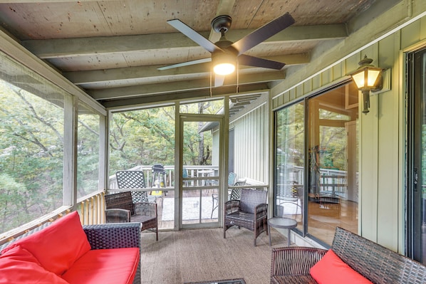 A covered porch with wicker furniture, a ceiling fan, and a view of the outdoors.