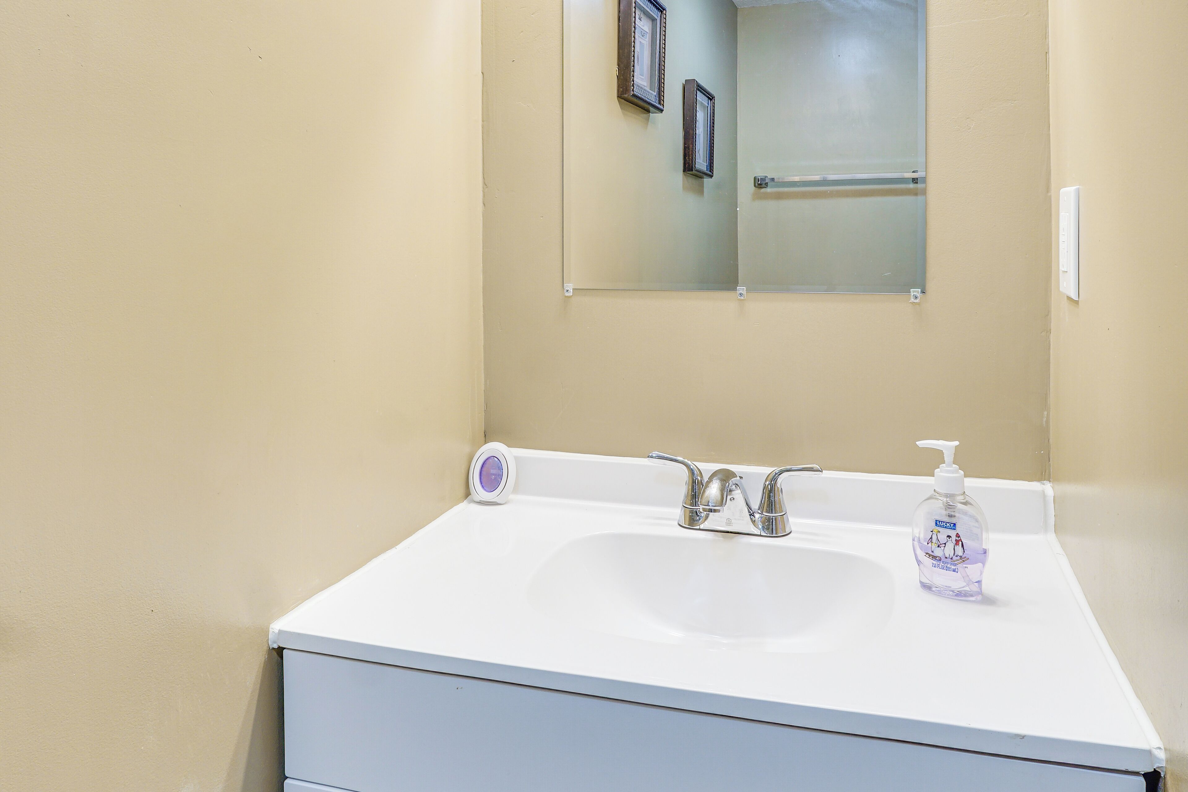 A bathroom with a white sink, a mirror, and a hand soap dispenser.
