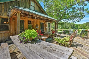 Un chalet rustique en bois, doté d’une véranda, de meubles de jardin et offrant une vue sur un paysage verdoyant et luxuriant.
