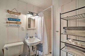 A bathroom with a toilet, sink, mirror, and towel rack.