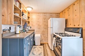 A compact kitchen with wooden cabinets, a gas stove, a refrigerator, and a sink.