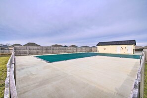 Ein Garten mit Schwimmbad, Holzzaun und einem kleinen Gebäude mit dunklem Dach.
