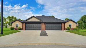A two-story house with a garage, a driveway, and a well-maintained lawn. - Family-friendly Ozark Villa - Centrally Located (Ozark)