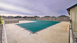 Un jardin avec une piscine, une clôture en bois et des maisons en arrière-plan.