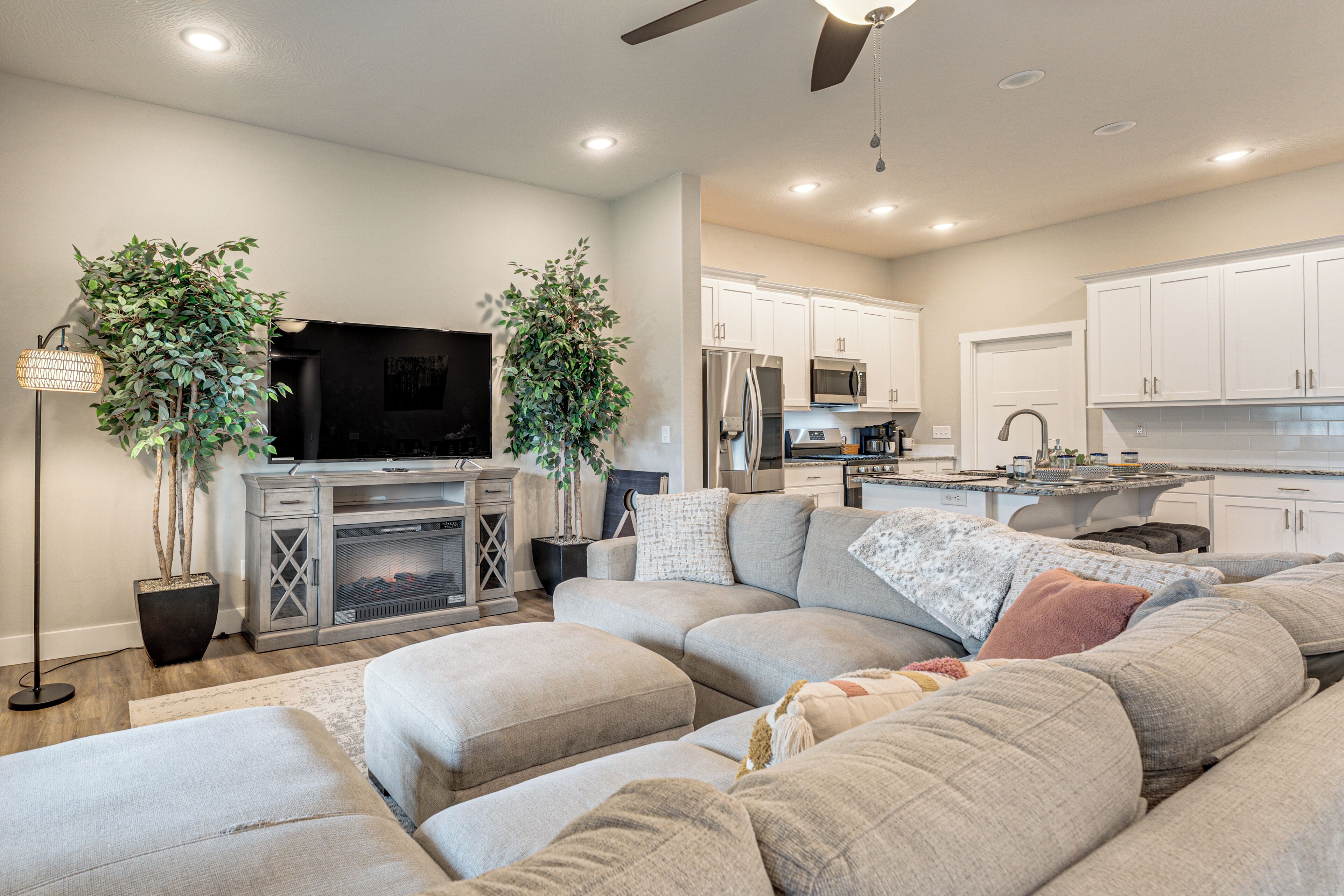A modern living room with a sectional sofa, a flat-screen TV, and a fireplace.