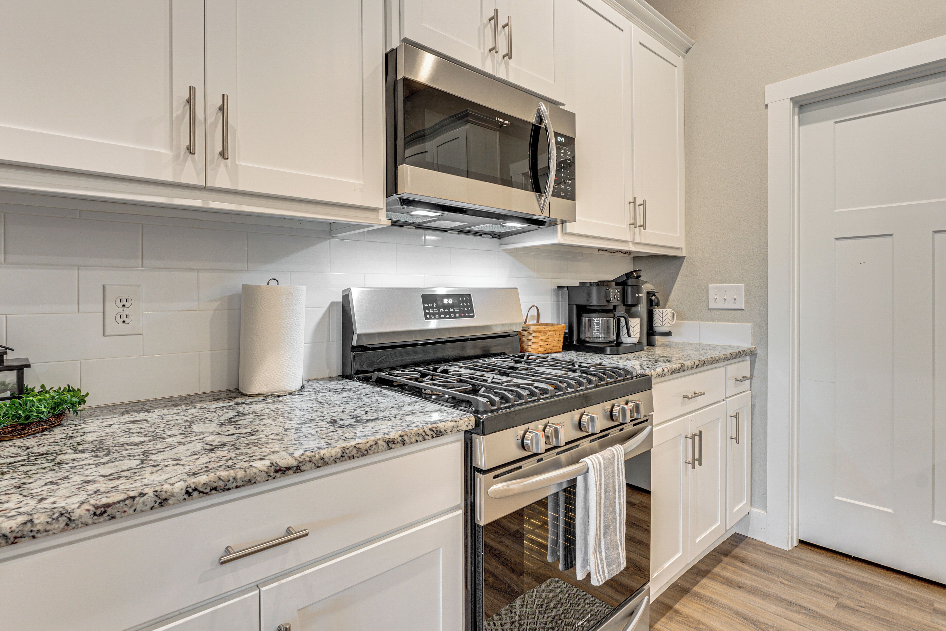 A modern kitchen with white cabinetry, a stainless steel range, and a granite countertop.
