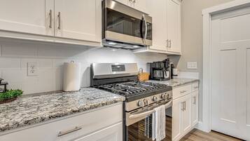 A modern kitchen with white cabinetry, a stainless steel range, and a granite countertop.