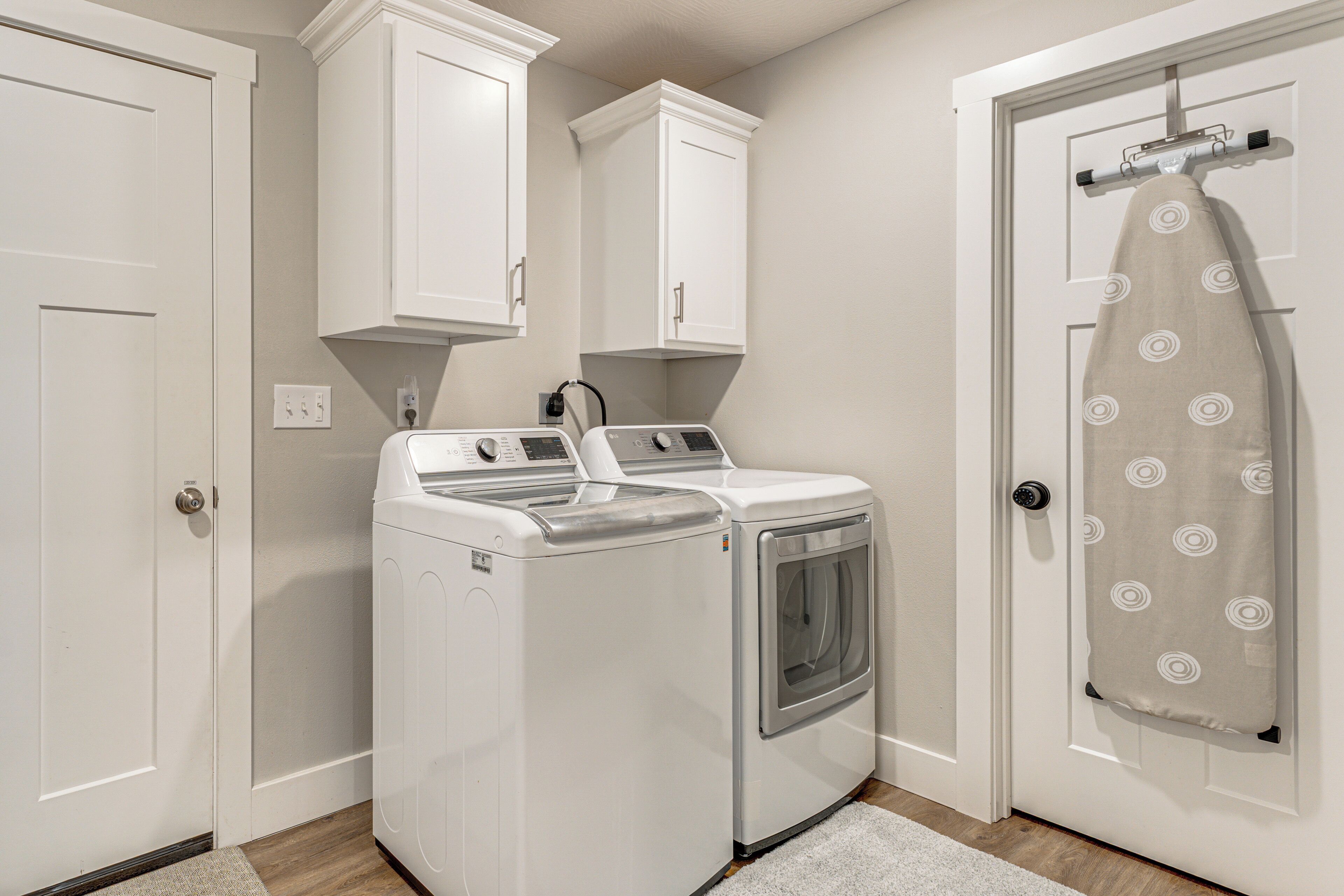 A laundry room with a washing machine and dryer, white cabinets, and a door with a towel hanging on a hook.