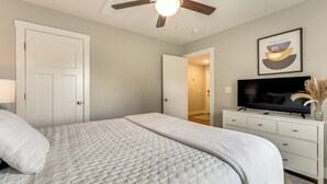 A bedroom with a bed, a ceiling fan, a television, and a framed picture on the wall. - Family-friendly Ozark Villa - Centrally Located (Ozark)