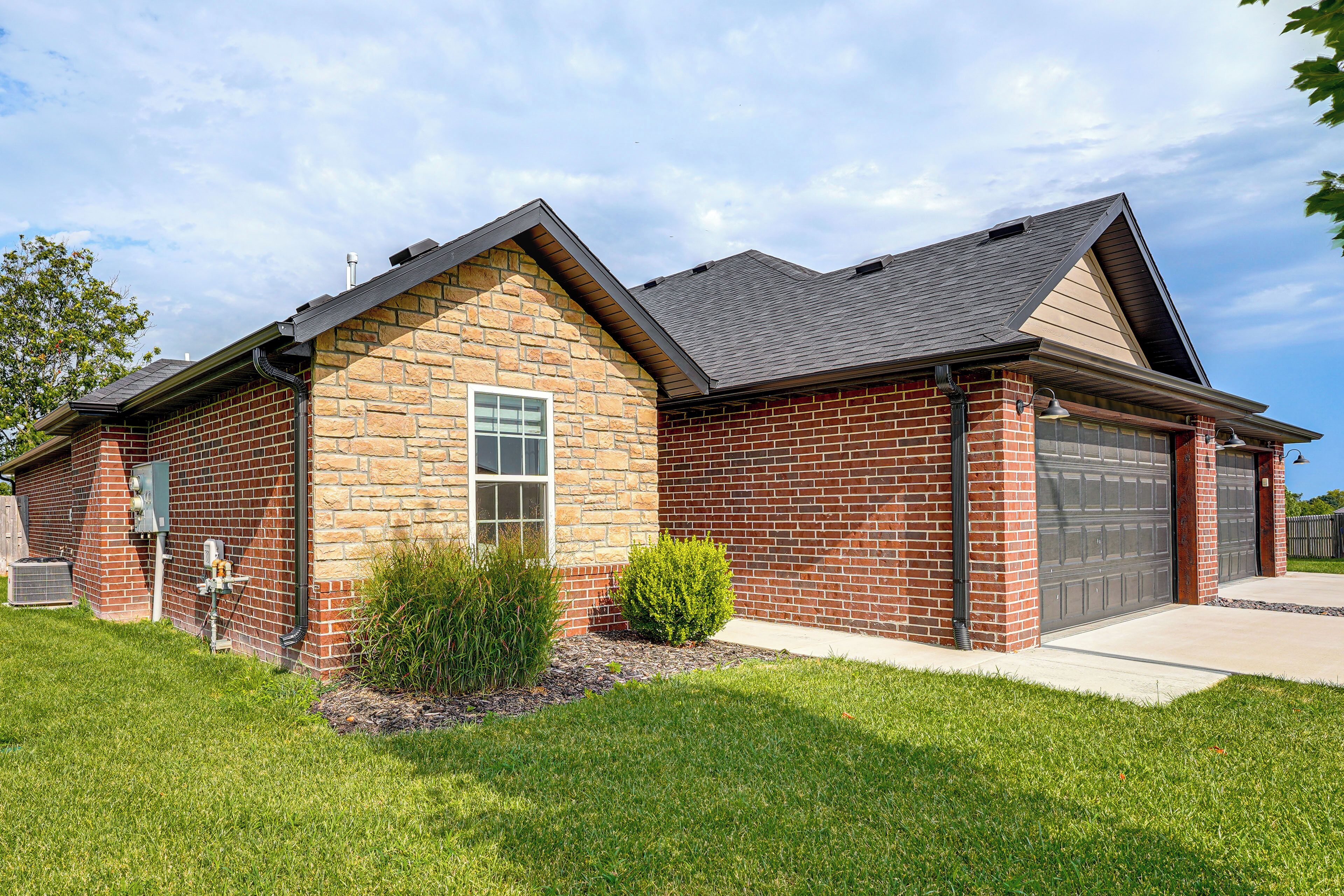 A two-story house with a brick exterior, a garage, and a well-maintained lawn.