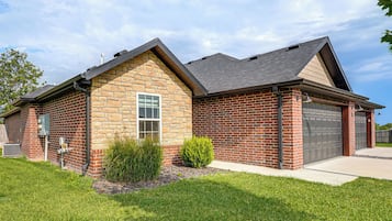 A two-story house with a brick exterior, a garage, and a well-maintained lawn.