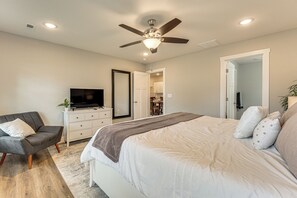 Quarto com cama, televisão, poltrona, cômoda e ventilador de teto.