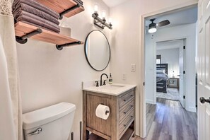 A bathroom with a toilet, sink, mirror, towel rack, and a ceiling fan. - Cottage w/ Fire Pit by Lake of the Ozarks Shootout (Osage Beach)