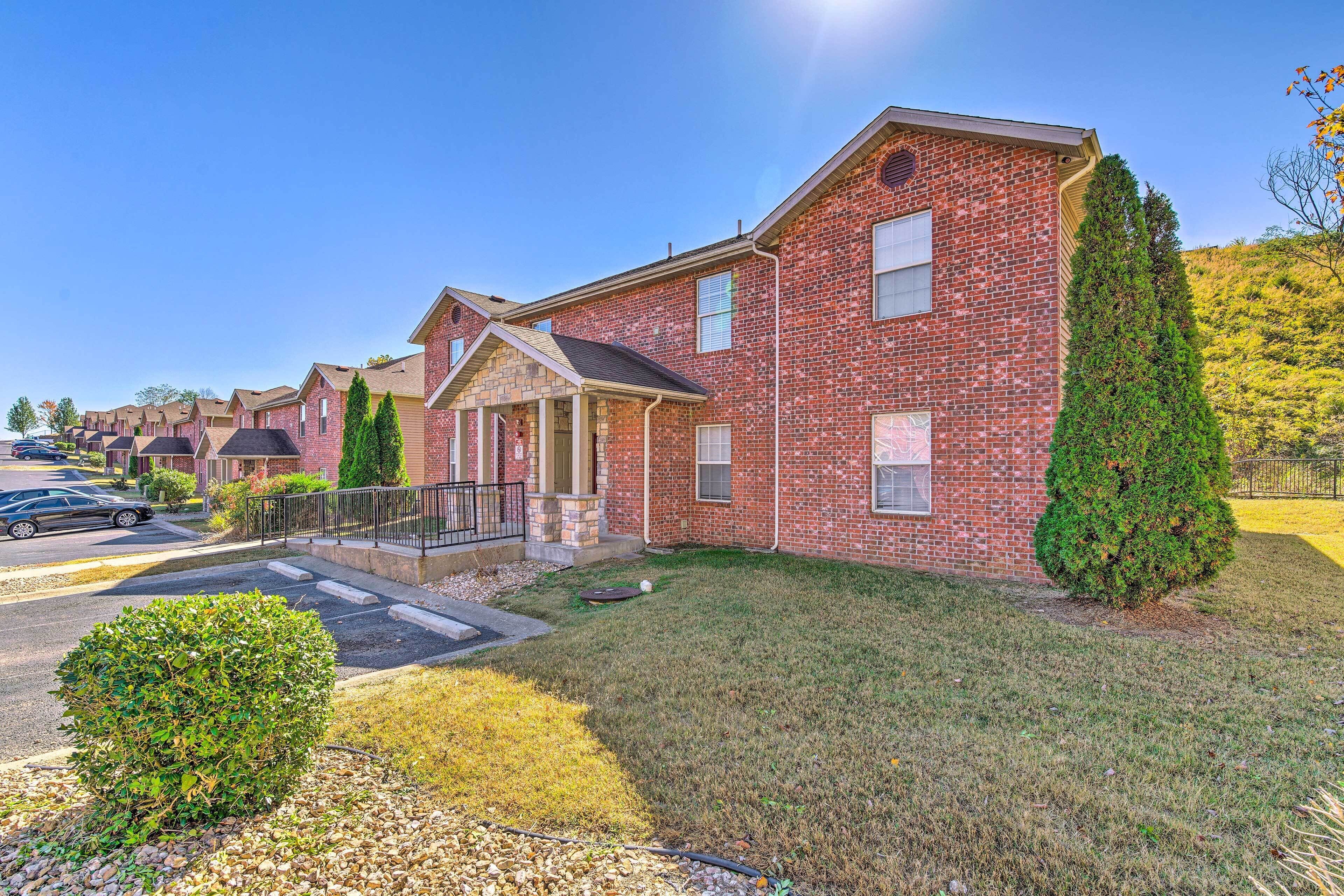 A two-story brick house with a front porch, a small front yard, and a driveway.