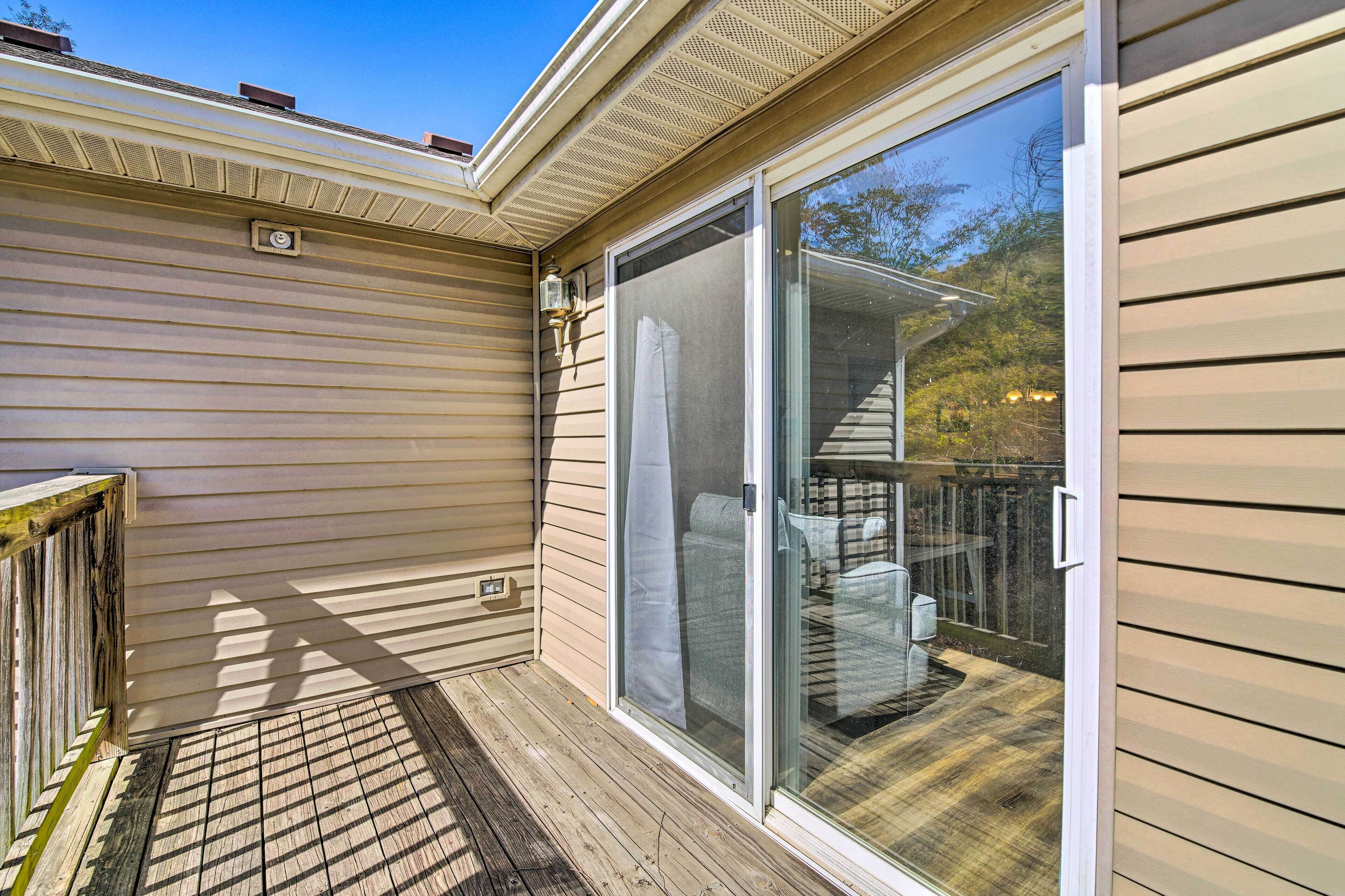 A covered deck with a sliding glass door leading to an outdoor seating area.