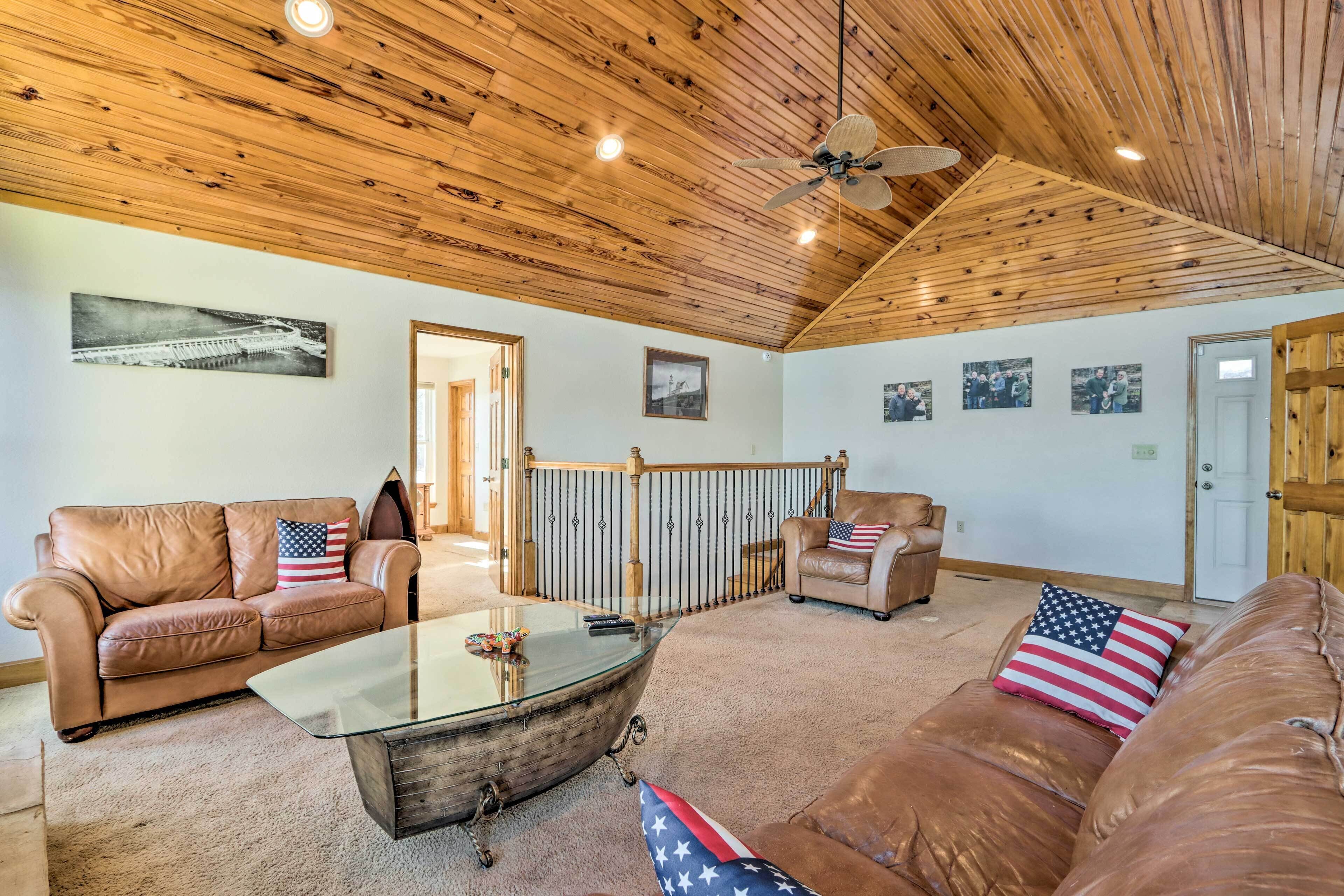 A spacious living room with leather sofas, a glass coffee table, and wooden ceiling beams.