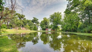 Un parc paisible avec un étang, des arbres et un petit bâtiment.